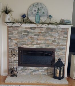 Glass door installation for gas fireplace with brick mantle decorated in living room of home and matching fireplace accessories