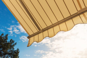 yellow retractable awning on the side of a home to protect the people and deck from sun's rays